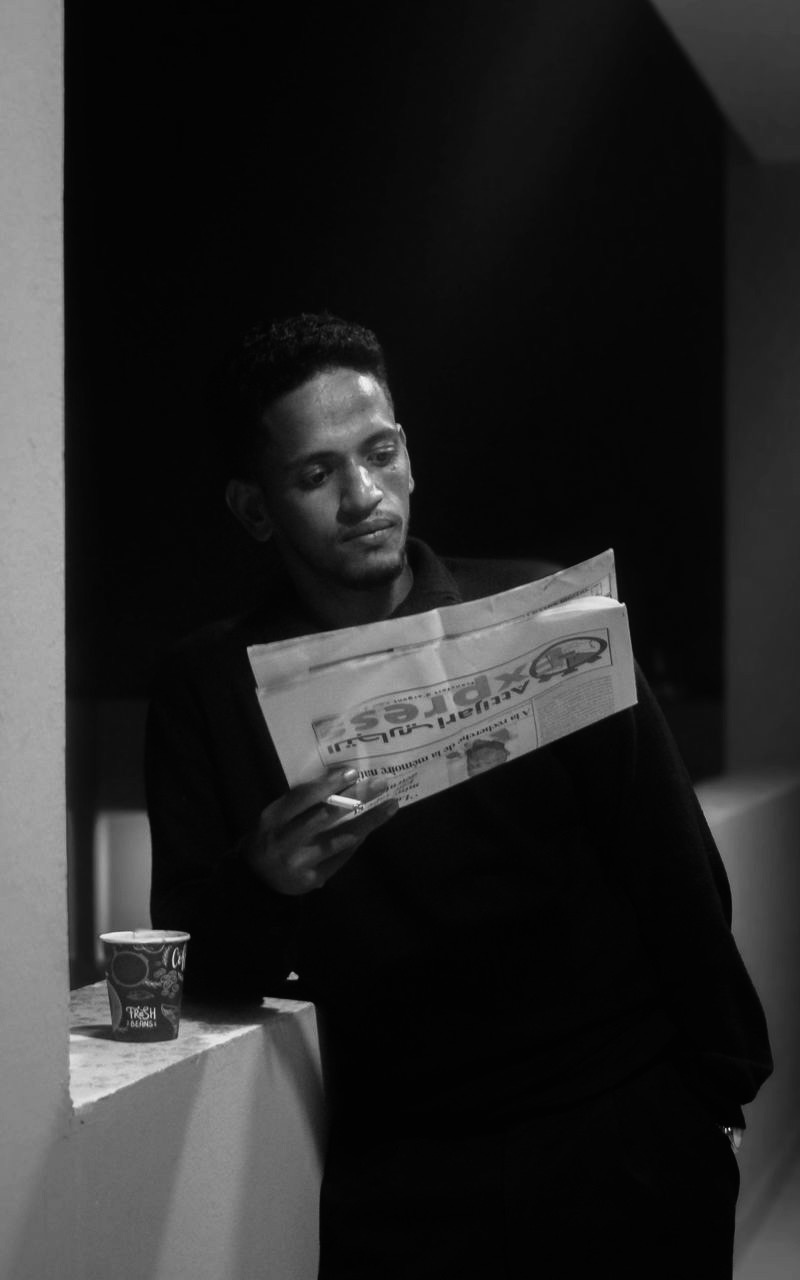 Ahmed reading the newspaper with espresso and a cigarette